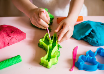 Child hands playing with colorful clay. Homemade plastiline. Plasticine. play dough. Girl molding modeling clay. Homemade clay.