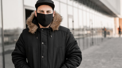 Men wears a black protective medical face mask being in the city during a coronavirus pandemic. Protection from viruses in the city.
