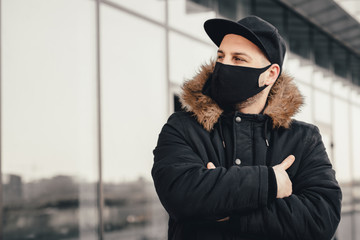 Men wears a black protective medical face mask being in the city during a coronavirus pandemic....