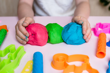 Child hands playing with colorful clay. Homemade plastiline. Plasticine. play dough. Girl molding...