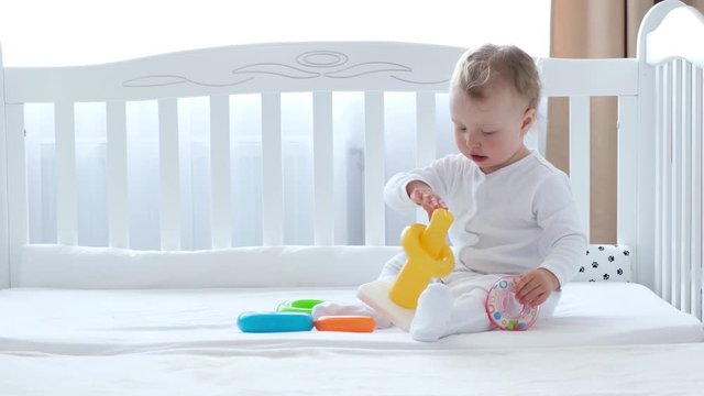 Baby girl playing with toys in bedroom.