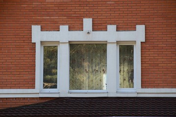 one large white window on the red brick wall of a house on the street