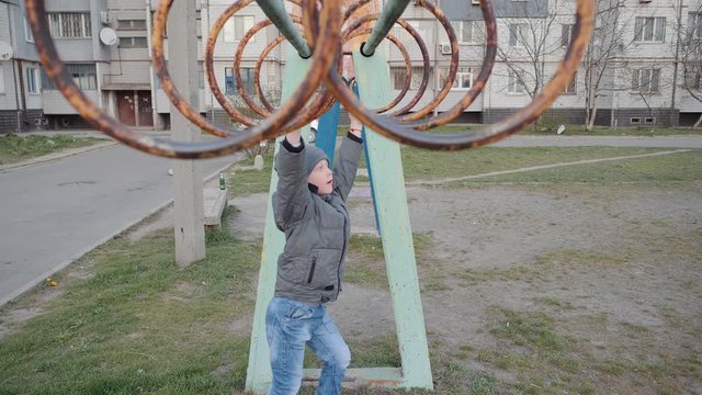 The boy on the monkey bars . The boy is on the treadmill which is located in the working quarter.