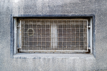 Rectangular basement or cellar window is tightened with wire metal mesh and grille. Technical floor...