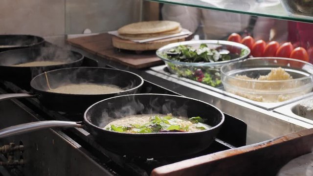 Four frying pans with steam in restaurant kitchen. Cooking classical Jewish Yemenite food. Making Lachuch. Slow motion. Beautiful cinematic steam on sunlight.