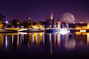 Fototapeta na wymiar Fantastic sky with huge moon over Wroclaw City, Odra river and reflections of historical buildings in it.