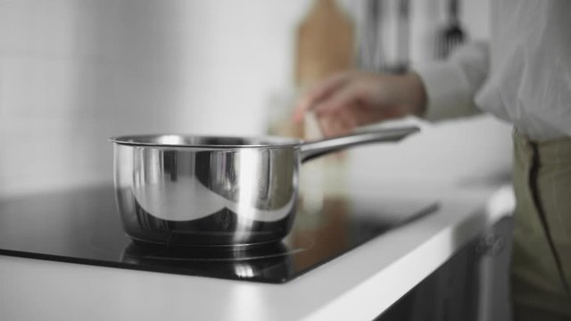 Close up of woman puts a pot and turned on induction cooker