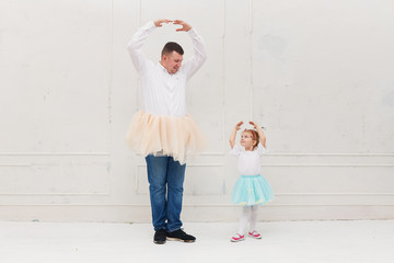 Big father and little daughter in tutu skirts dancing like ballerinas. Remote home dance training....