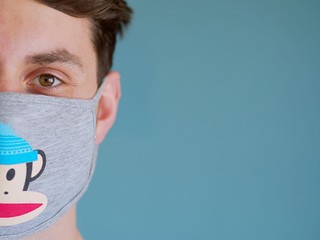 Closeup of a caucasian man face wearing funny monkey face protection mask with a brown eyes and hair, since new coronavirus outbreak for self protection.