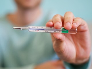 Closeup of a man holding a thermometer for measuring body temperature degrees Celsius at 38,5 background.