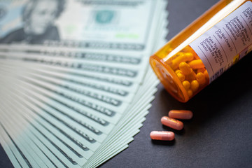 Pills and Pill Bottle on a table with 20 Dollar Bills