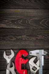 A set of tools for plumber on black wooden boards prepared by professional master before repair or construction