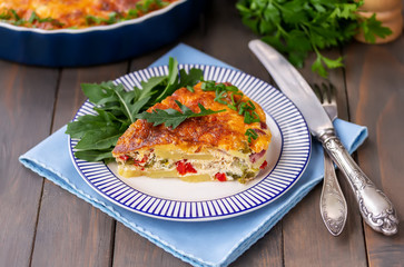 One piece of Spanish tortilla with arugula on a plate. Dark wooden background, selective focus.