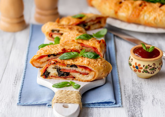 Sliced Italian Stromboli stuffed with salami, cheese, black olive and tomato sauce. Wooden...