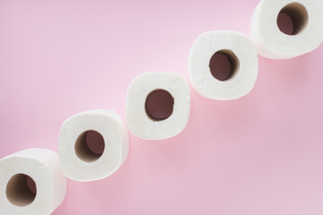 Toilet paper rolls in line, on pink pastel background - coronavirus outbreak scene. Shortage/panic buying concept. 