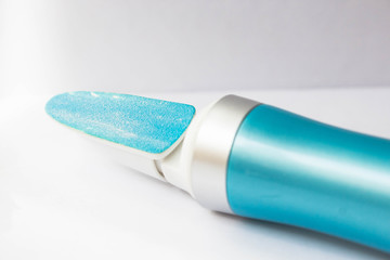 A tool for manicure at home. Blue electric nail file with replaceable attachment with diamond coating on a white background close up
