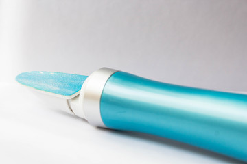 A tool for manicure at home. Blue electric nail file with replaceable attachment with diamond coating on a white background close up