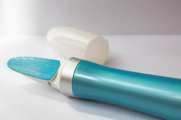 A tool for manicure at home. Blue electric nail file with replaceable attachment with diamond coating on a white background close up