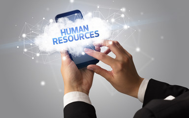 Female hand touching smartphone with HUMAN RESOURCES inscription, cloud business concept