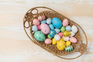 Top view of basket with colorful Easter eggs. Wooden background