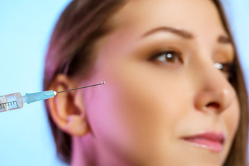 Syringe for beauty injection on the background of the face of a girl closeup. Beautiful female model with healthy skin
