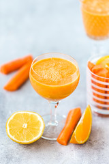 Freshly Made Organic Carrot-Orange Juice on grey background, vertical format. Selective focus