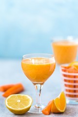 Freshly Made Organic Carrot-Orange Juice on blue background, vertical format. Selective focus
