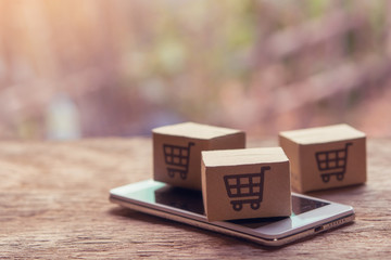Online shopping - Paper cartons or parcel with a shopping cart logo and smartphone on wood table...