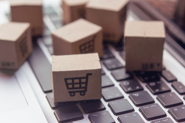 Fototapeta premium Online shopping - Paper cartons or parcel with a shopping cart logo on a laptop keyboard. Shopping service on The online web and offers home delivery.