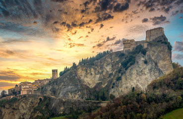 Obraz premium Sunset view of San Leo fortress on a hilltop with cannon towers in Italy