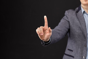 A man in a jacket abstractly presses a finger on a black background.