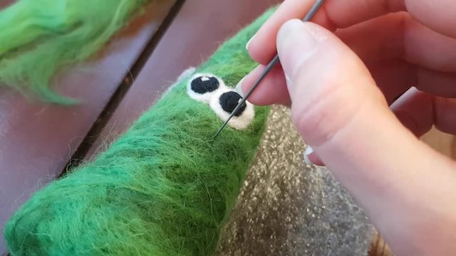 Dry felting. Needlework. Work with a needle on the wool on the table. Toy in the form of a funny Christmas tree. Semiproduct.