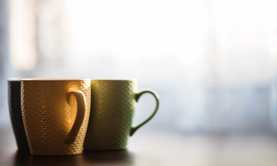 Cups. Colored cup standing on wooden table. Blurred background. The sun is shining on the cup.