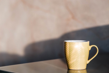 Cup. Blue cup standing on a wooden table. Blurred background. The sun is shining on the cup.