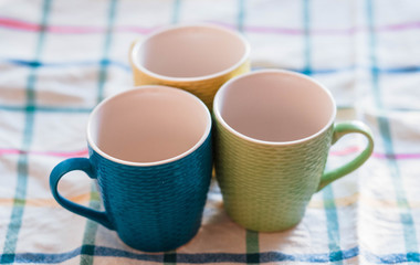 Cups. Colored cups lying side by side and lying on a towel. Blurred background. The sun is shining on the cup.