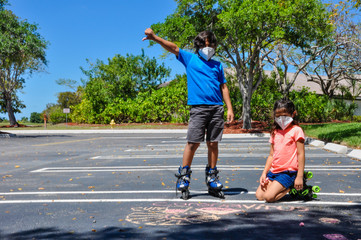 Obraz premium coronavirus kids mask boy thumbs down girl stare heads up side to side stare rollerblades pointing drawing chalk outside arts roller skates covid19