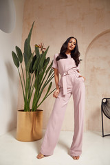 Beautiful sexy brunette woman tanned skin face cosmetic makeup wear pink suit pants for date walk...