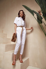 Beautiful woman fashion model brunette hair tanned skin wear white overalls button suit sandals...
