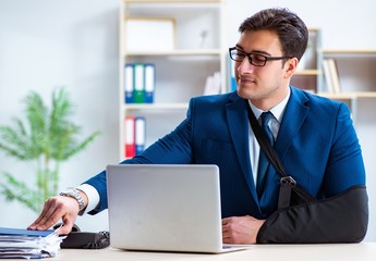 Businessman with broken arm working in office