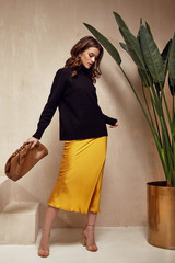 Fashion model brunette hair wear yellow silk dress skirt black top sandals high heels accessory bag...