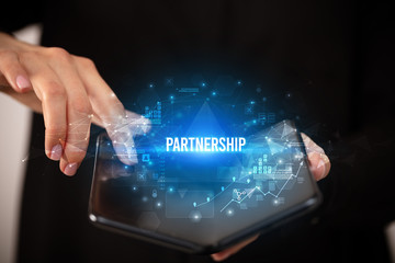 Businessman holding a foldable smartphone with PARTNERSHIP inscription, business concept