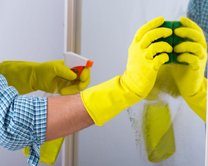The young man cleaning mirror at home hotel