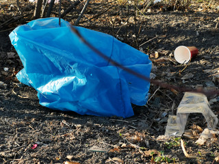 Blue plastic garbage bag on the ground. Close up. Enviroment pollution.