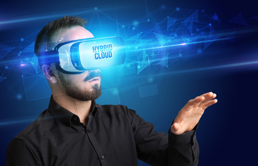 Businessman looking through Virtual Reality glasses with HYBRID CLOUD inscription, cyber security concept