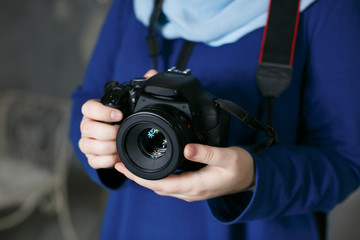 Girl in a scarf hold in her hands a reflex camera in a blue dress