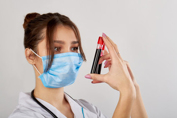 Young female doctor holding two tubes filled with blood. Analizying blood tests. Isolated on white.