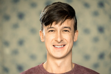 Portrait of a young man with dark hair with a smile. Horizontal frame