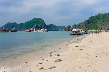 Ships unload people on the island of monkeys. Many people on the beach. Ha Long Bay in Vietnam