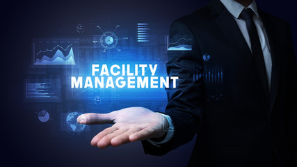 Hand of Businessman holding FACILITY MANAGEMENT inscription, business success concept