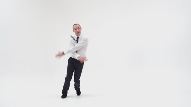 A cheerful office worker is dancing a break dance. The businessman stands on one hand with his knees drawn up, then stands with his hands on his belt